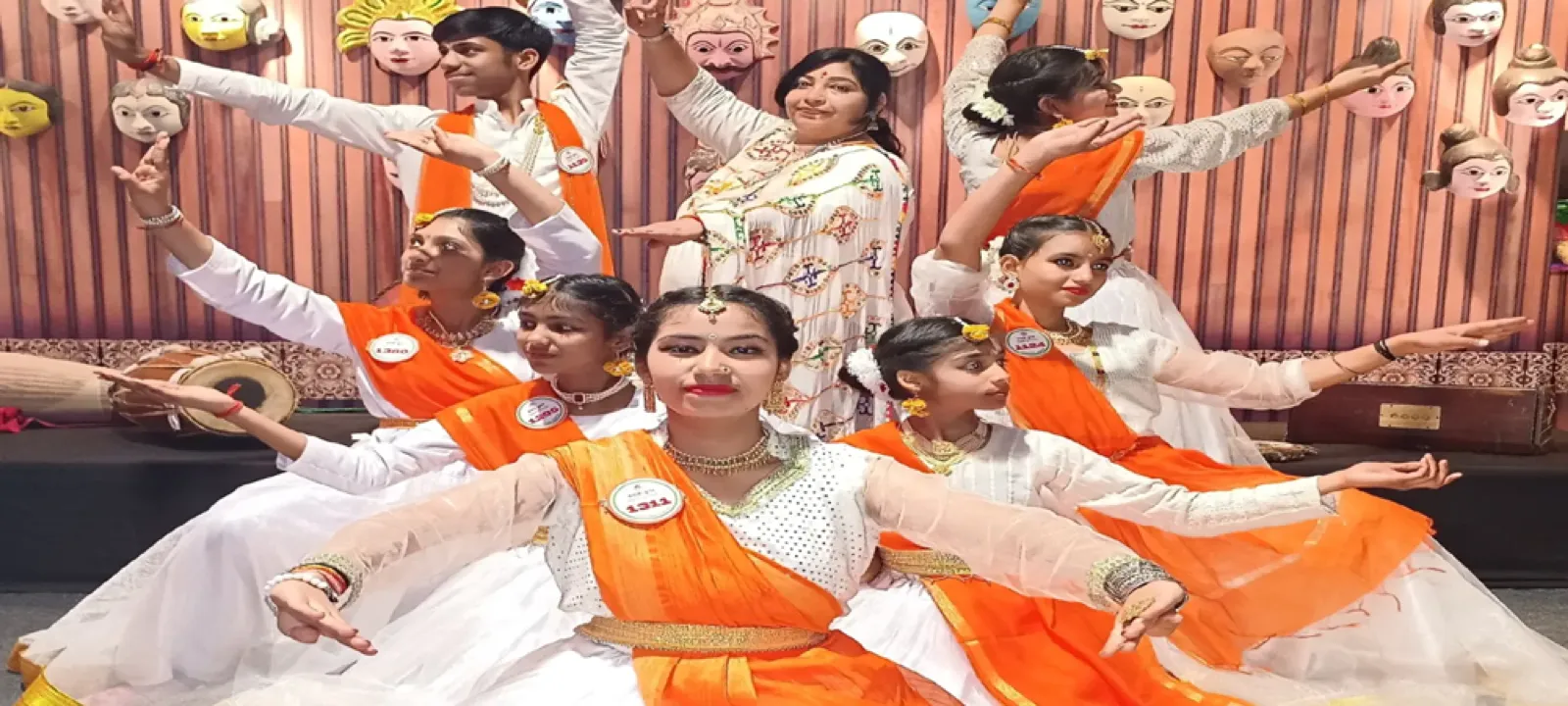 Kathak students performing in white and saffron costumes